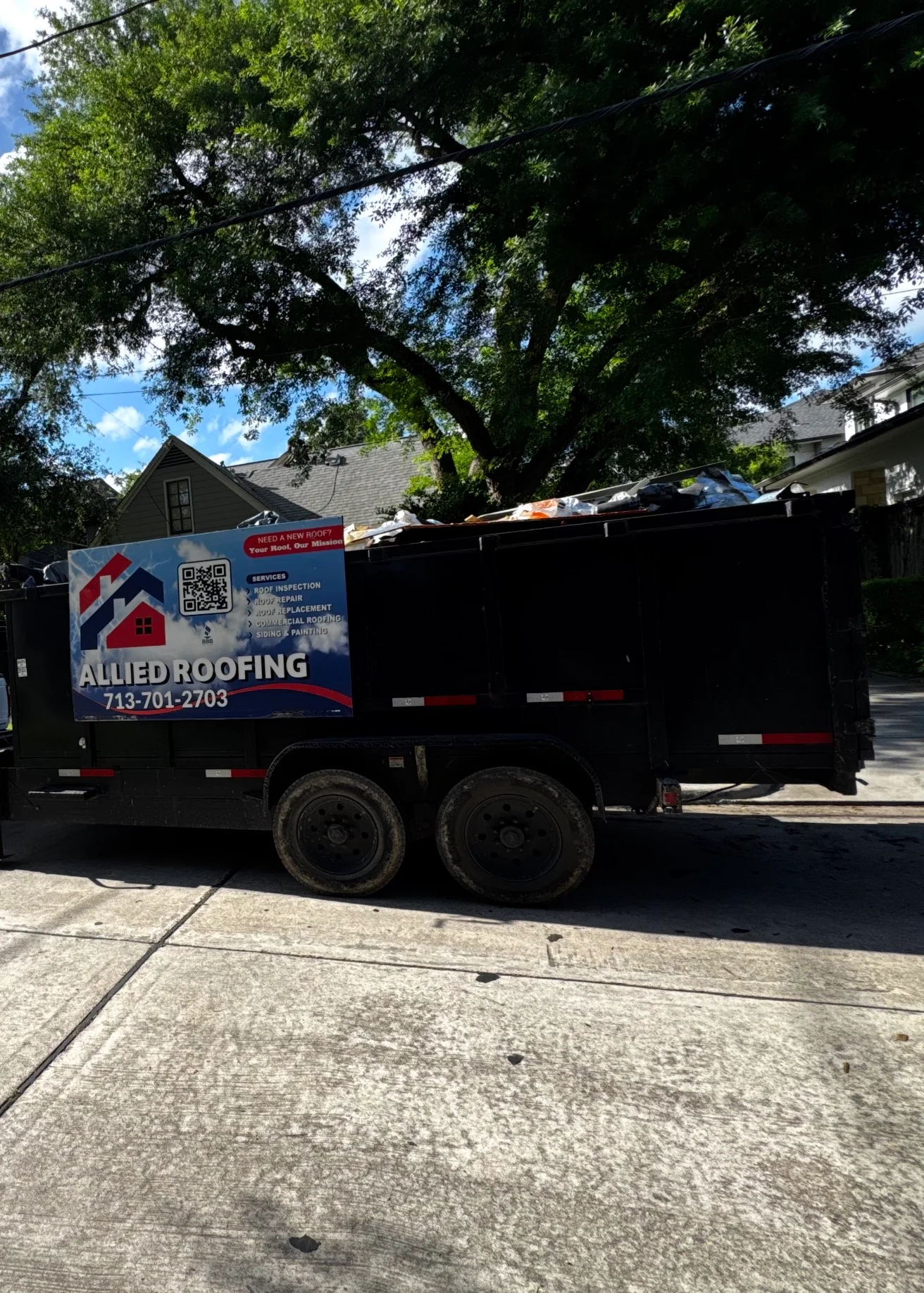 Residential roof replacement with new asphalt shingles installed on home with mature trees