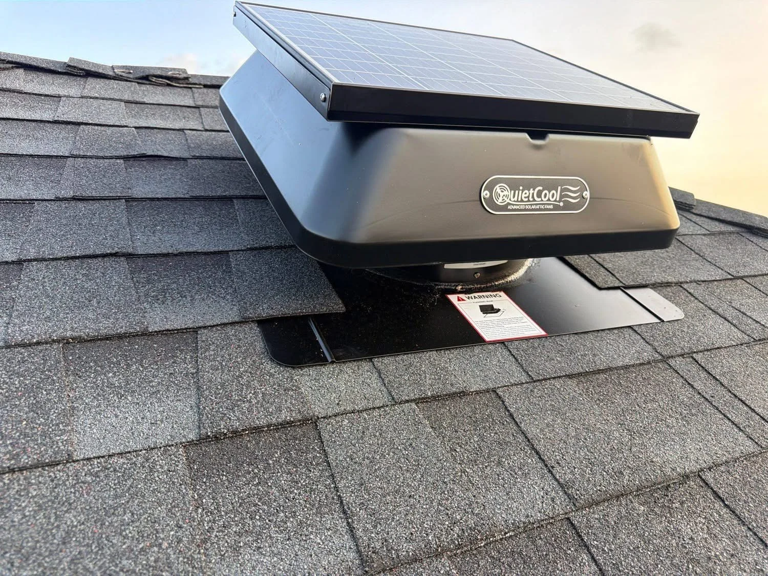 Solar attic fan with integrated panel installed on gray asphalt shingle roof