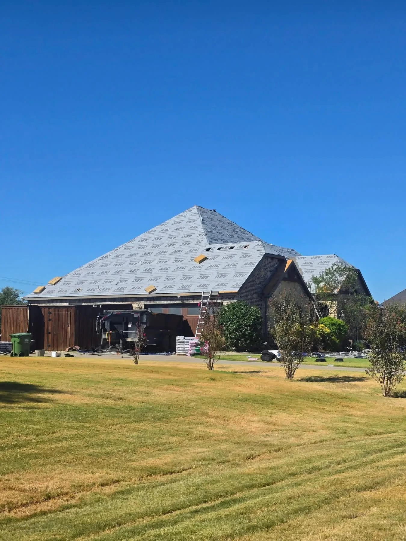 Residential roof replacement with protective underlayment and yellow roof vents installed on pyramid-style roof