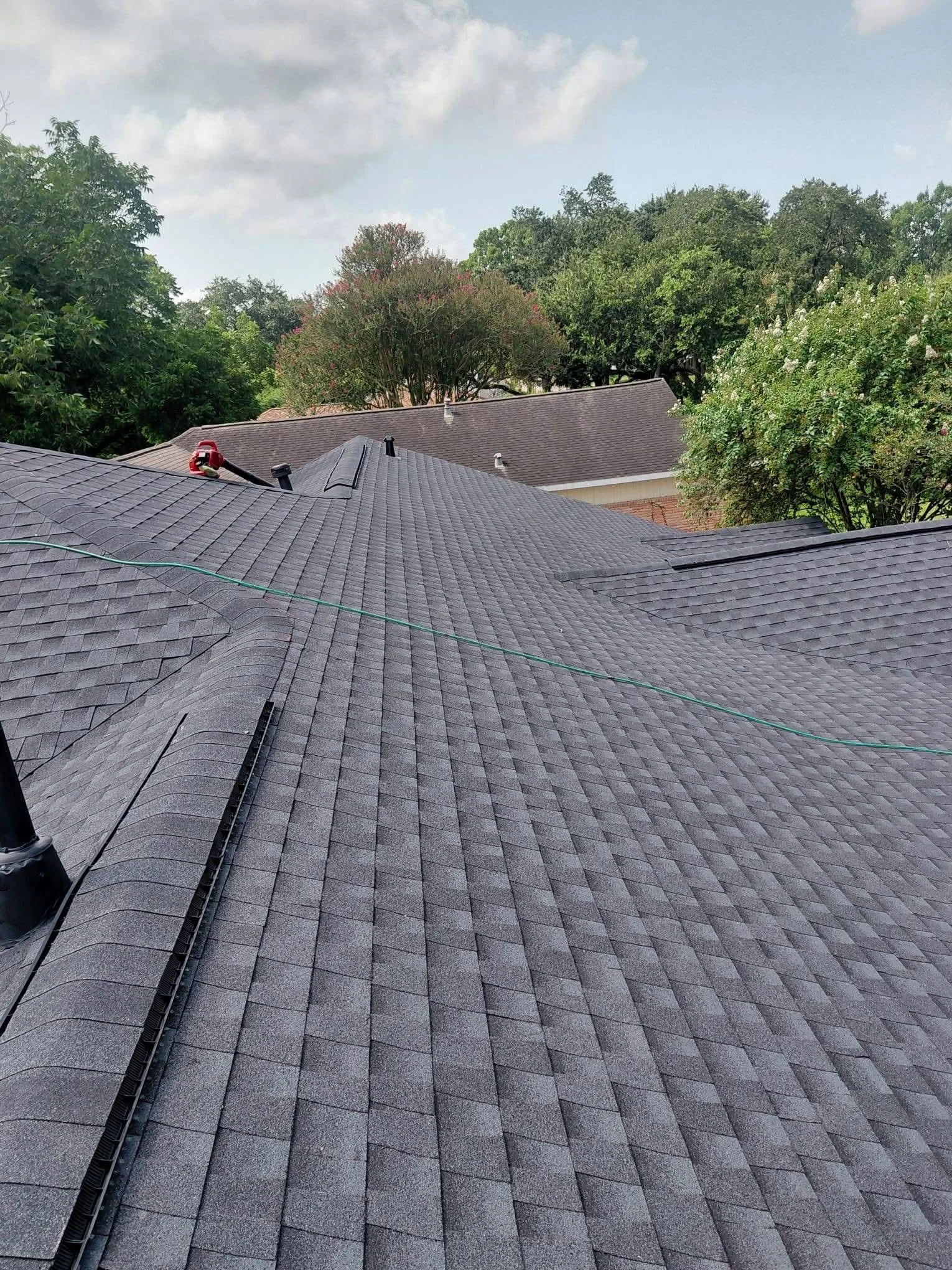 Charcoal gray architectural shingles installed on multi-slope residential roof with metal flashing and valleys