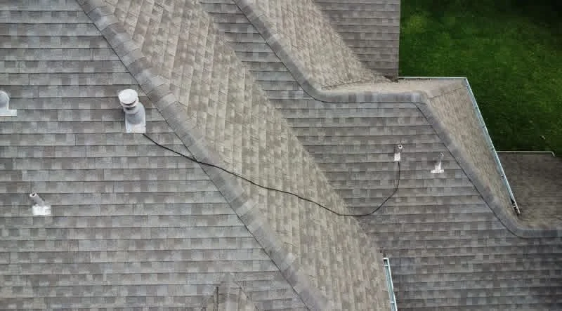 Gray architectural shingles with valley flashing and roof vents on multi-slope residential roof