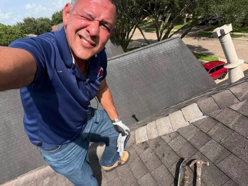 Roofing contractor inspecting asphalt shingle roof with white PVC vent pipe visible