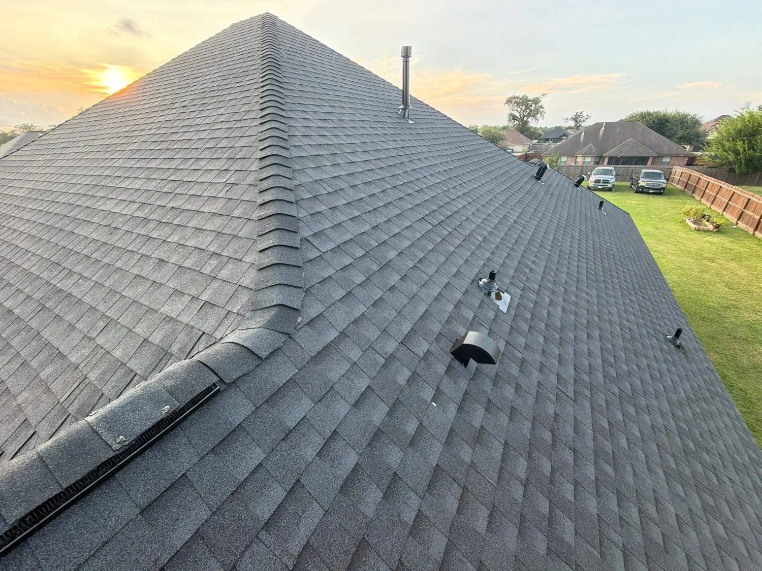 Charcoal gray architectural shingles installed on multi-pitched roof with ridge vent and gutters