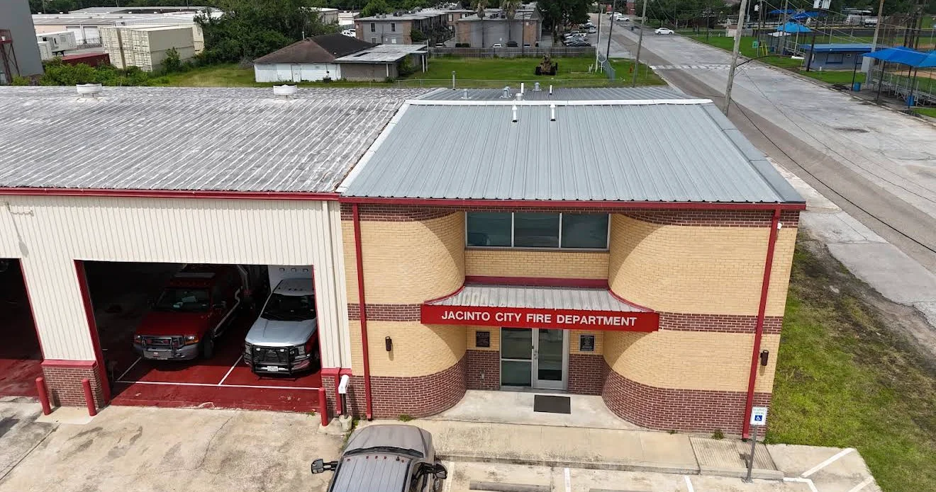 Standing seam metal roof installation on commercial brick building with red trim
