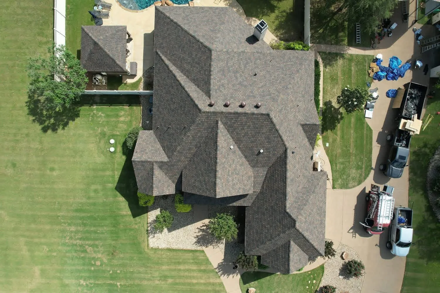 Aerial view of completed residential roof with gray dimensional shingles and multiple roof planes