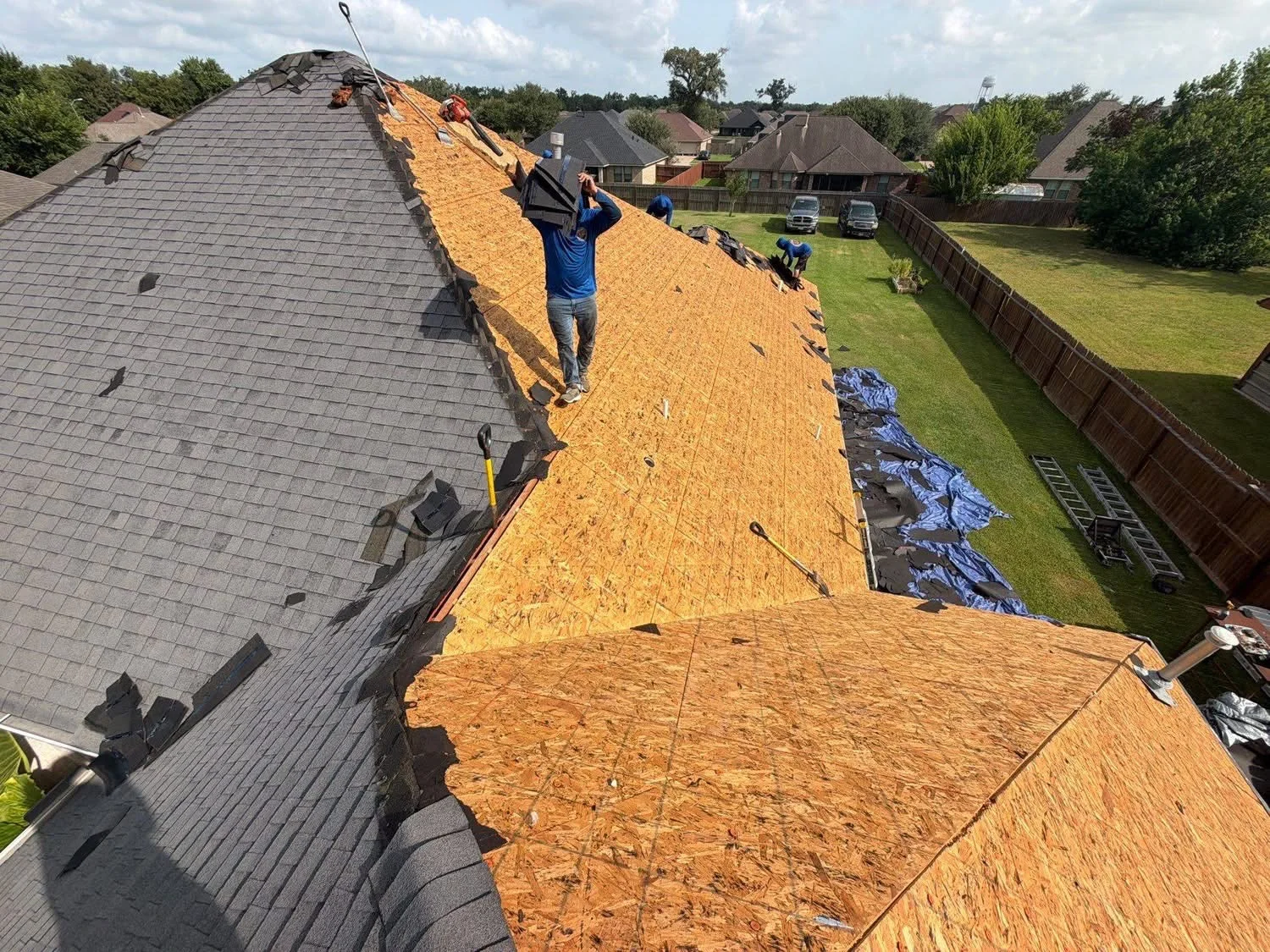 Roof replacement in progress with OSB decking and new shingle installation on pitched residential roof