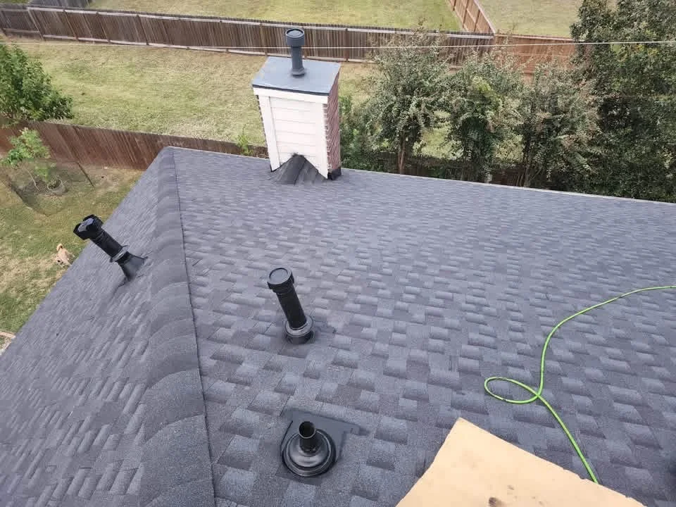 Gray architectural shingles with roof vents and chimney flashing installed on residential roof