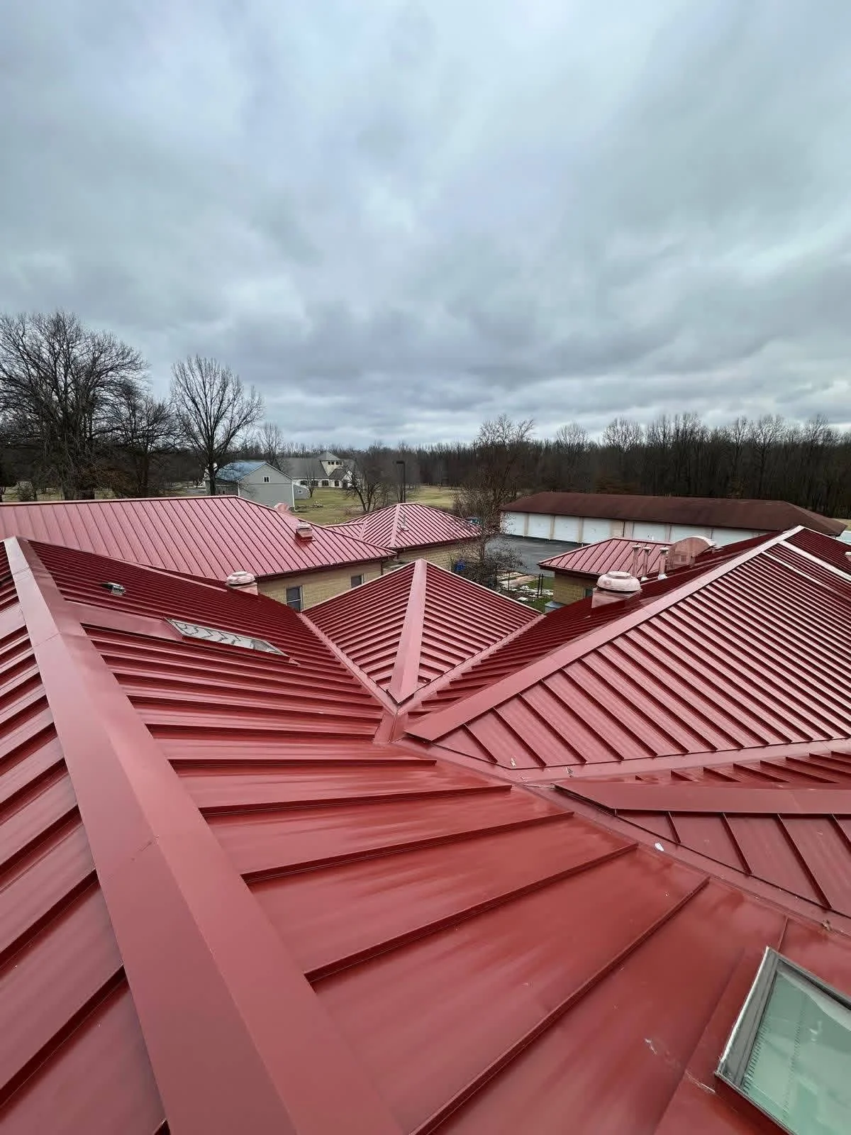 Red metal standing seam roof with multiple planes and ridge details