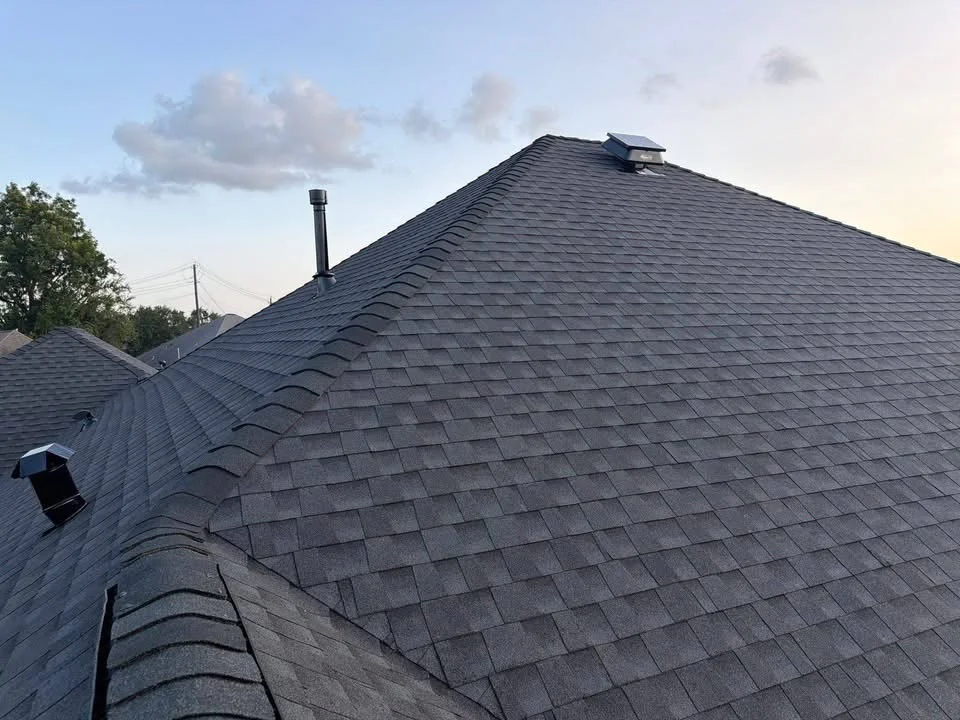Charcoal gray architectural shingles installed on multi-plane roof with ridge vents and flashing