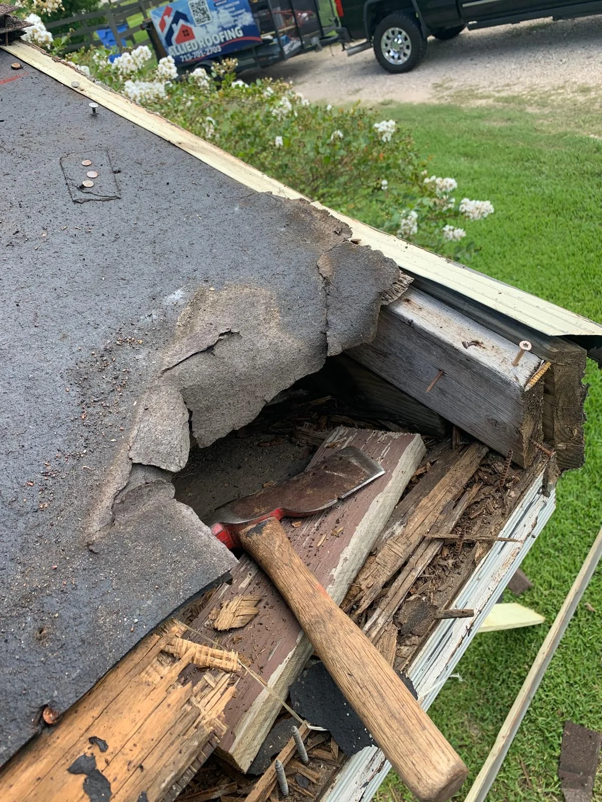 Roof edge with removed shingles exposing rotted wood decking and fascia board replacement work