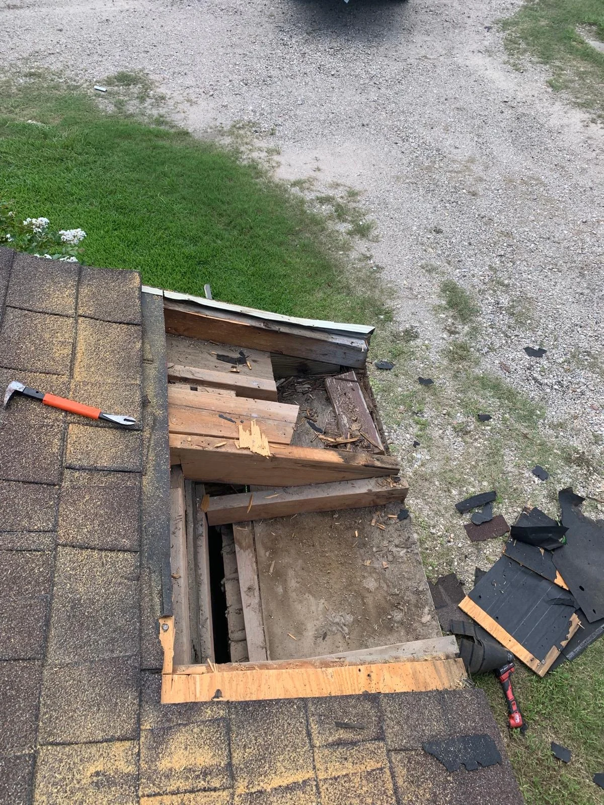 Roof vent opening with removed shingles, exposed wooden decking, and new plywood and metal flashing installation