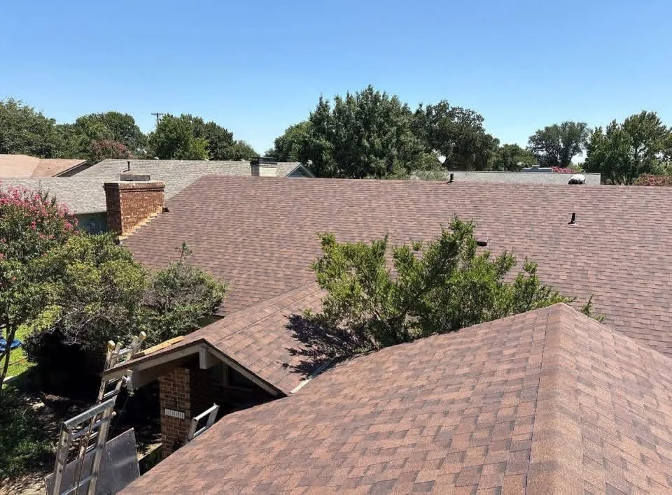 Newly installed brown architectural asphalt shingle roof with brick chimney and multiple roof planes