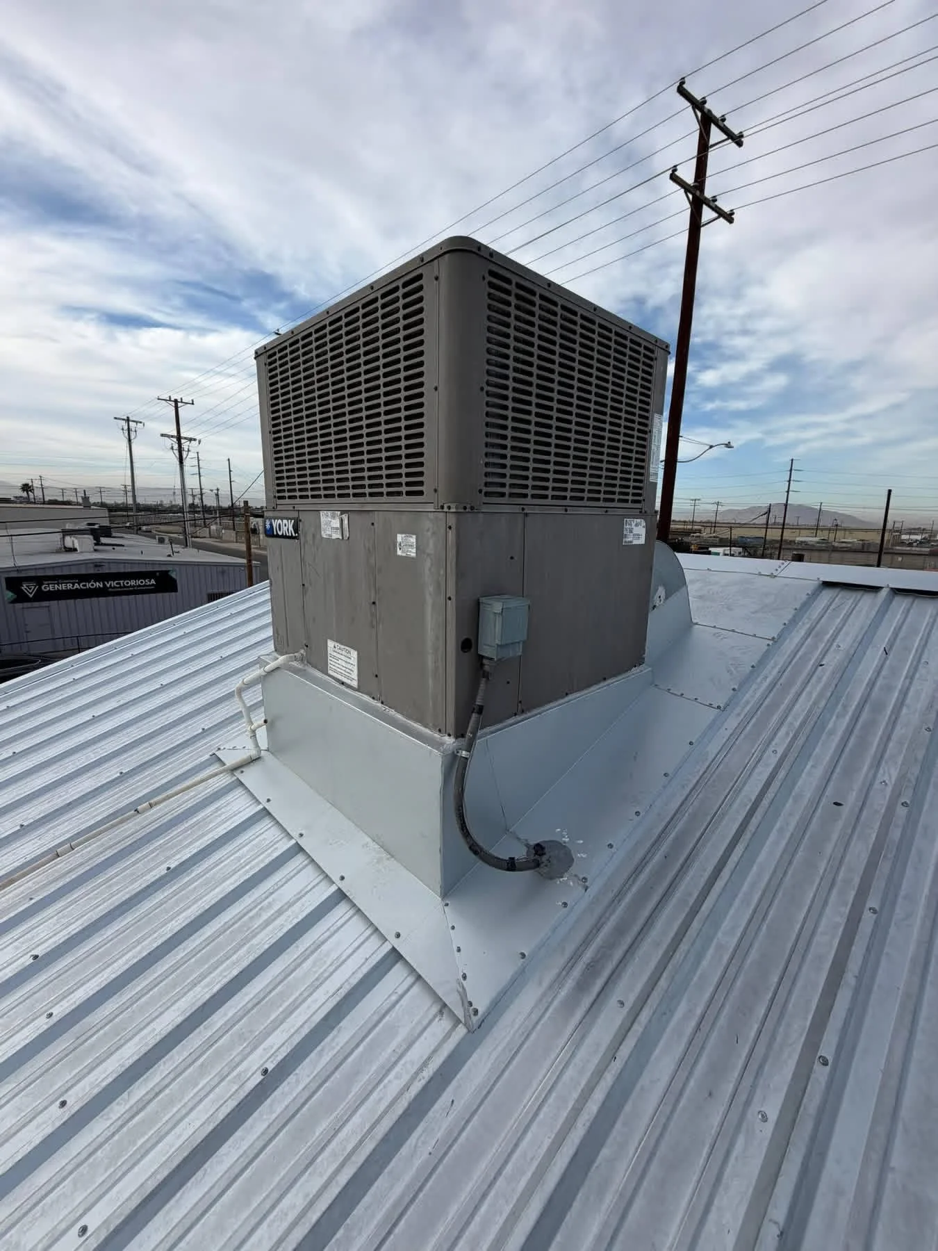 York HVAC unit mounted on metal standing seam roof with concrete pad and flashing