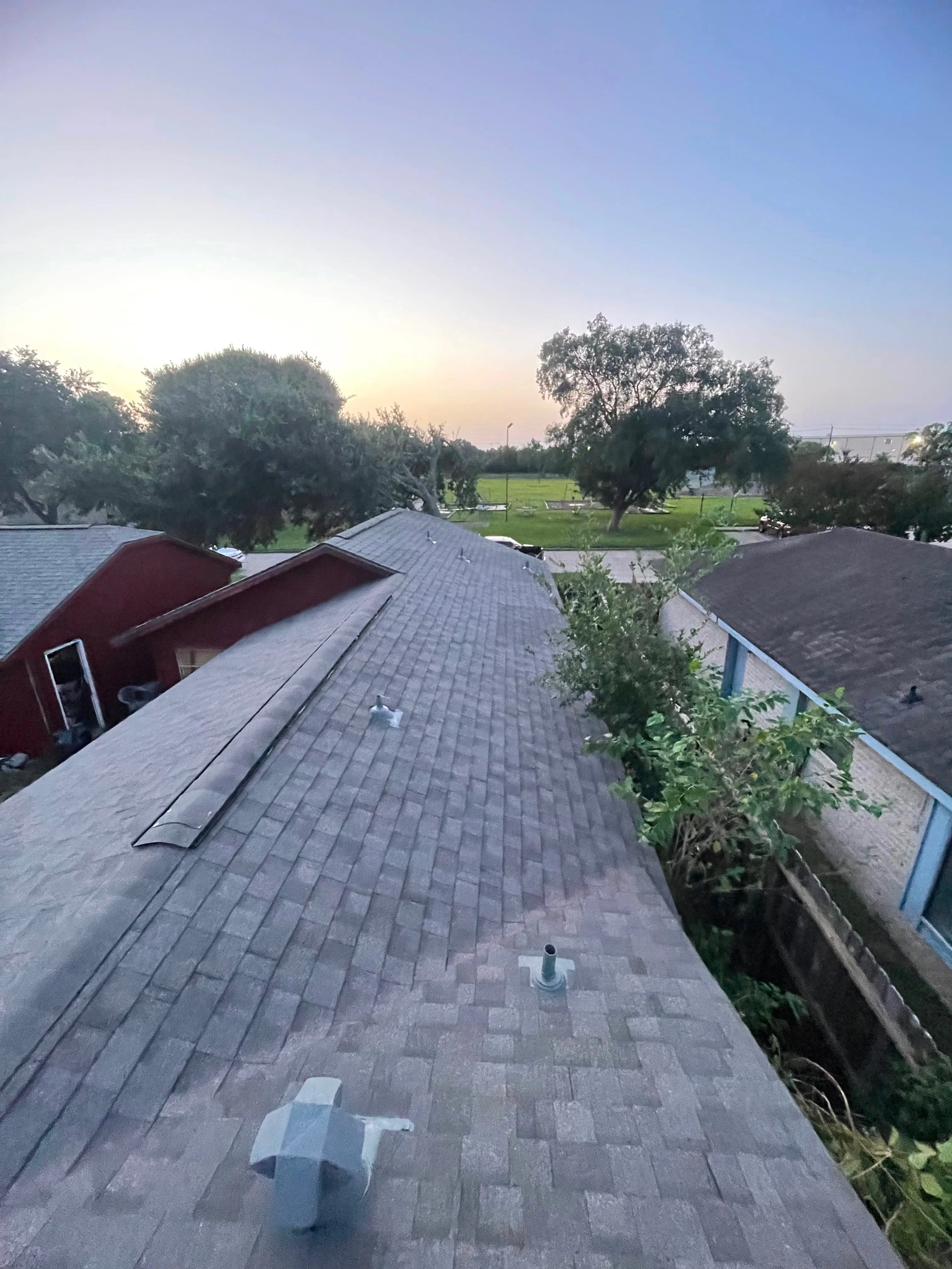 Newly installed charcoal asphalt shingle roof with ridge vents and proper flashing