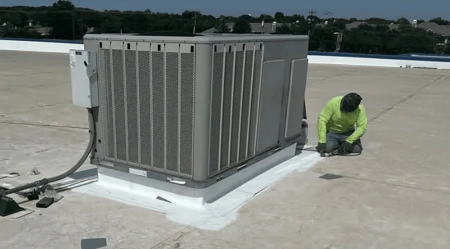 HVAC condenser unit installed on white membrane flat roof with curb base