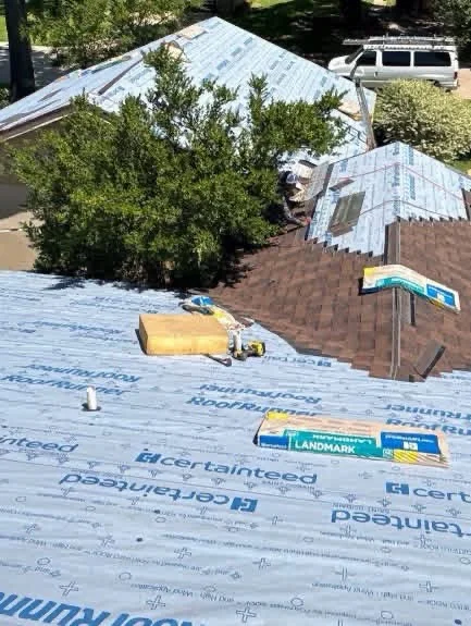 Roof replacement in progress with blue Certainteed underlayment and brown asphalt shingles