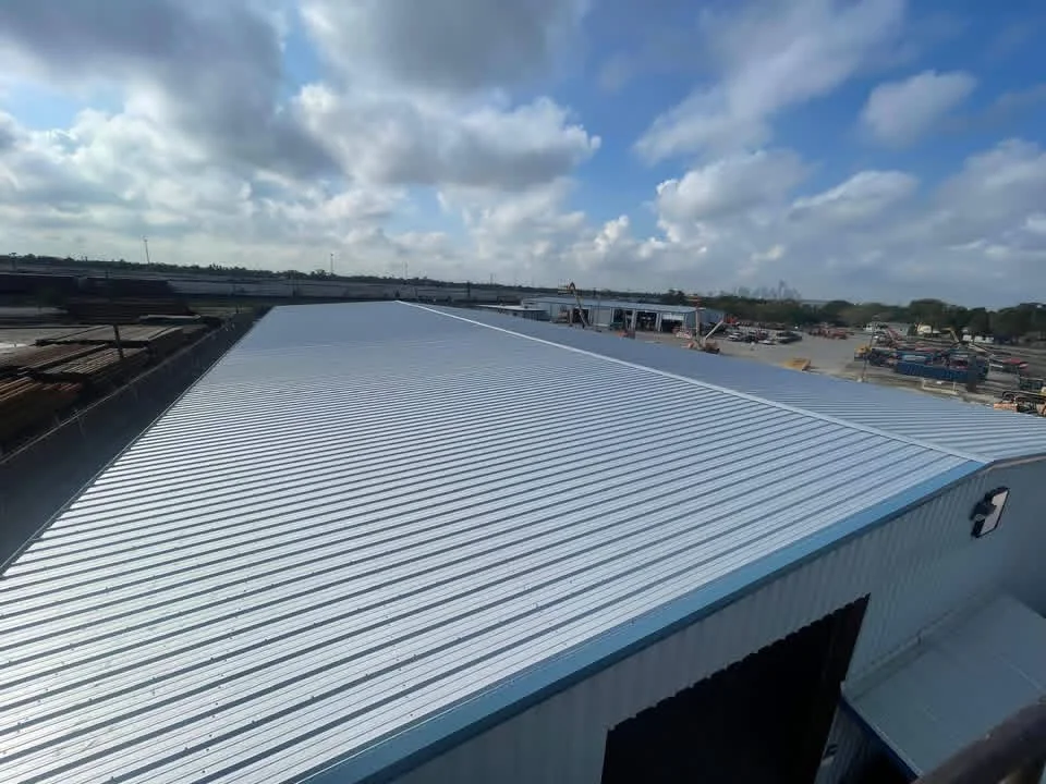 White standing seam metal roof installation on commercial building with blue trim