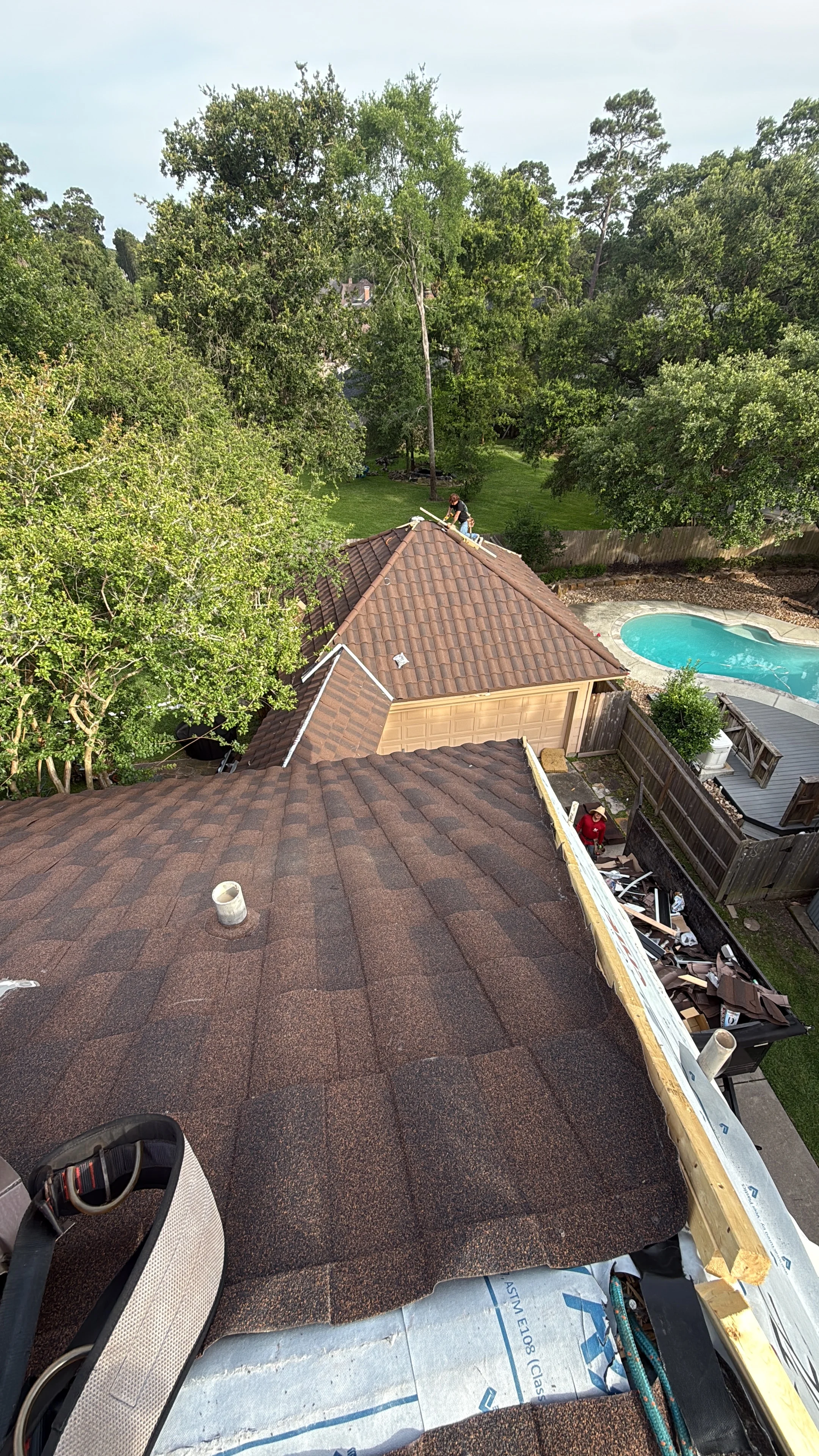 Brown architectural shingles installed on multi-plane residential roof with white trim and gutters